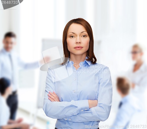 Image of smiling businesswoman with crossed arms at office