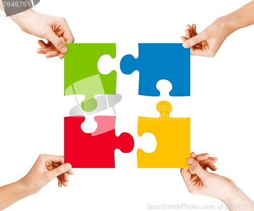 Image of four hands connecting puzzle pieces