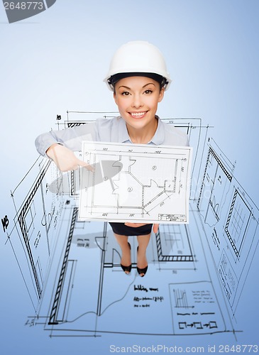 Image of businesswoman in helmet showing with blueprint