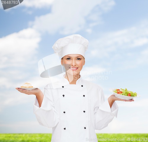 Image of smiling female chef with salad and cake on plates