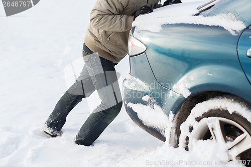 Image of closeup of man pushing car stuck in snow