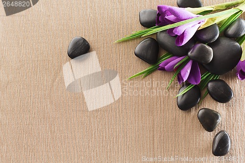 Image of massage stones with flowers on mat