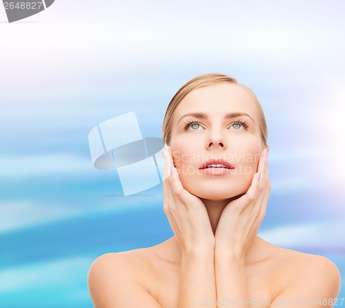 Image of beautiful woman touching her face and looking up