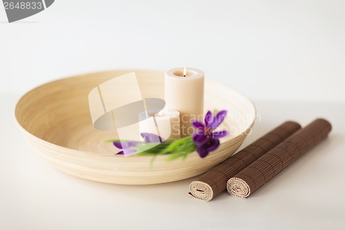 Image of candles and iris flowers in wooden bowel and mat