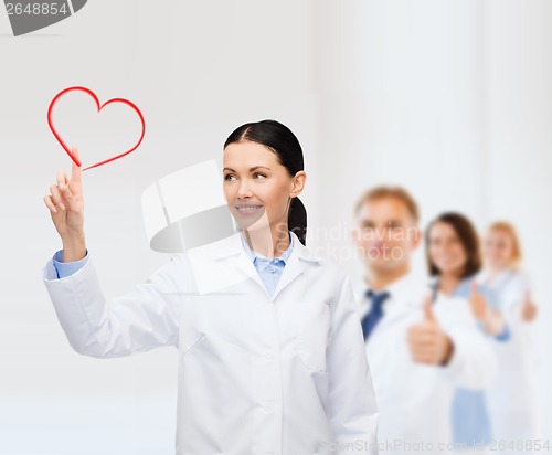 Image of smiling female doctor pointing to heart