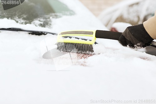 Image of closeup of man cleaning snow from car