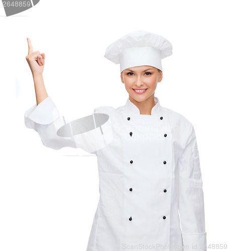 Image of smiling female chef pointing finger to sonething