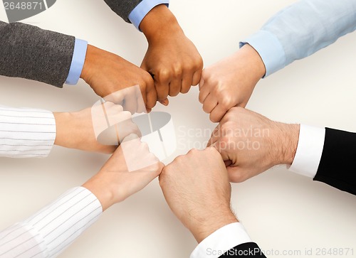 Image of closeup of businesspeople hands in fists in circle