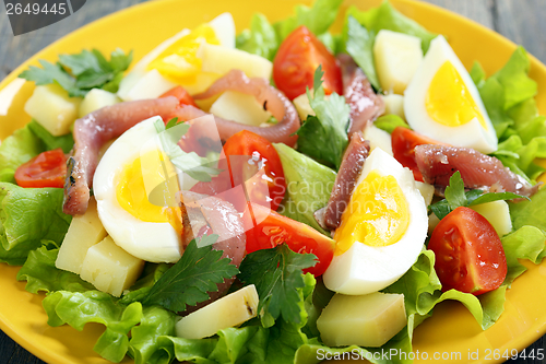 Image of Salad with anchovies on a yellow plate. 