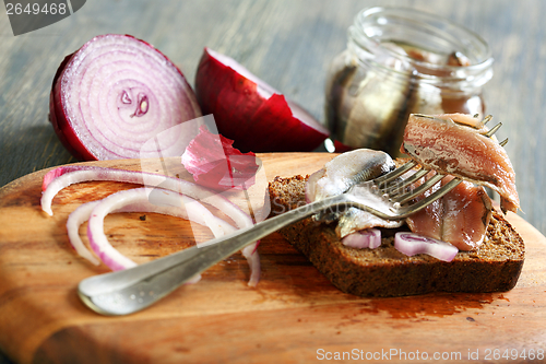 Image of Fork with anchovies, rye bread and red onion.