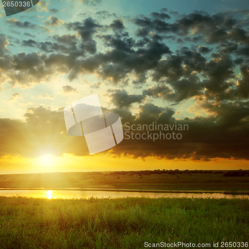 Image of orange sunset with dark clouds over river