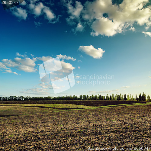 Image of dark sky with clouds over plowed field