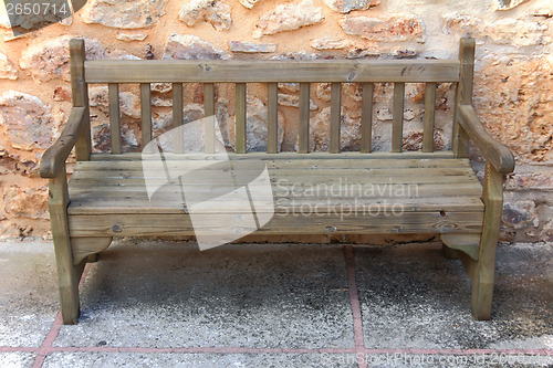 Image of old wooden bench near stone wall