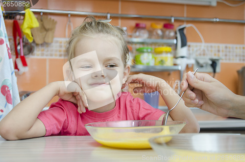 Image of Girl eating porridge in the kitchen