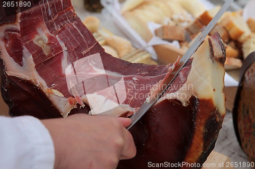 Image of A hand cutting prosciutto