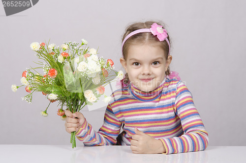 Image of Girl with a bouquet of flowers sitting at table