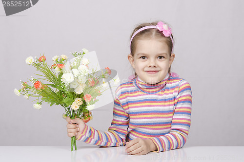 Image of Girl with a bouquet of flowers sitting at table