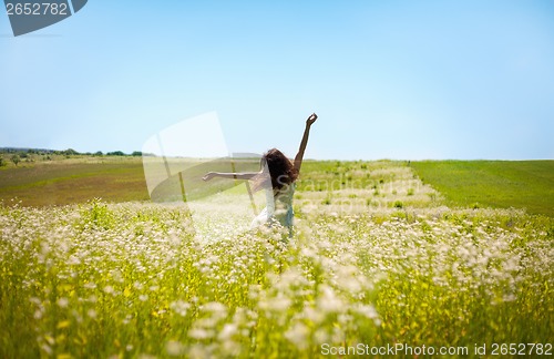 Image of Girl lifting her hands up in the air runs across the field