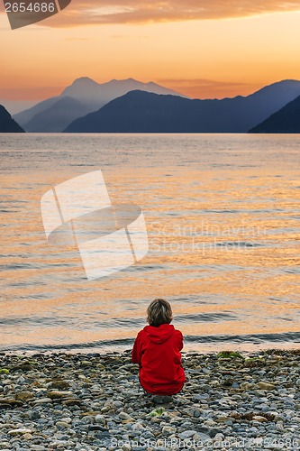 Image of Woman enjoying beautiful sunset landscape on fjord