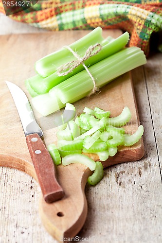 Image of bundle of fresh green celery stems and knife