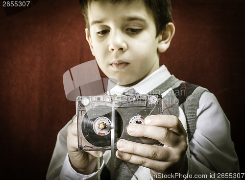 Image of Rolled cassette strip with a pencil. Boy hold cassette tape.