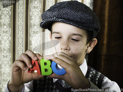 Image of Child in vintage clothes hold letters a b c