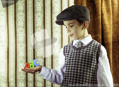 Image of Child in vintage clothes hold letters a b c