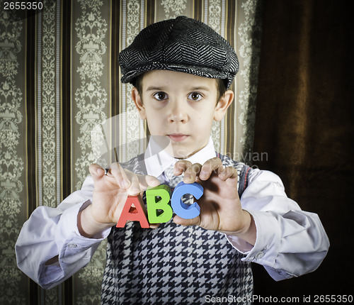 Image of Child in vintage clothes hold letters a b c