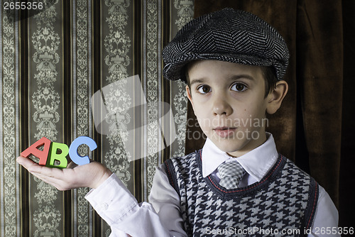 Image of Child in vintage clothes hold letters a b c