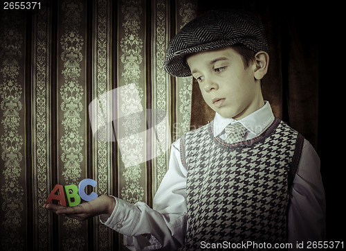 Image of Child in vintage clothes hold letters a b c