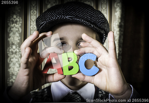 Image of Child in vintage clothes hold letters a b c