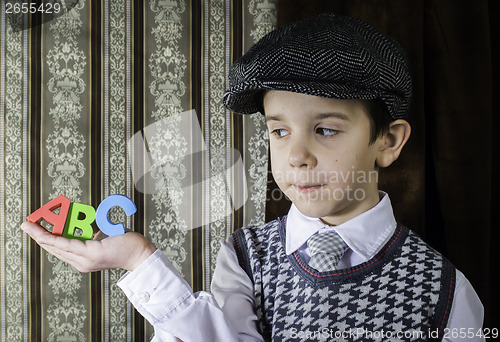 Image of Child in vintage clothes hold letters a b c