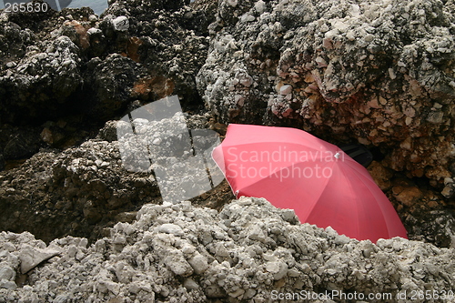 Image of Red parasol hidden among rocks