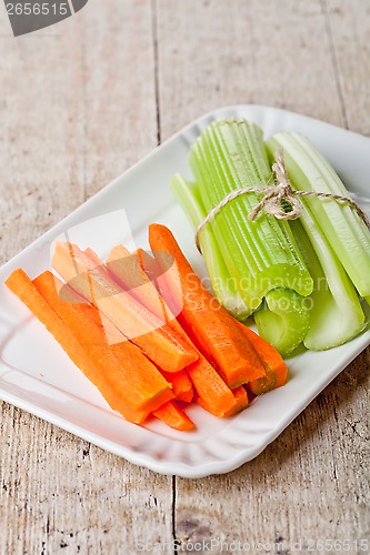 Image of bundle of fresh green celery stems and carrot 