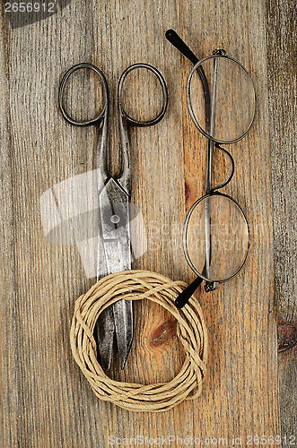 Image of old scissors, glasses and hank of packthread over wooden texture