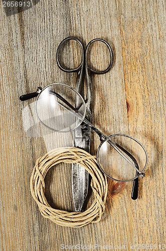 Image of old scissors, glasses and hank of packthread on wooden backgroun
