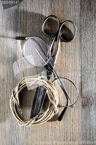 Image of old scissors, glasses and hank of packthread on wooden backgroun