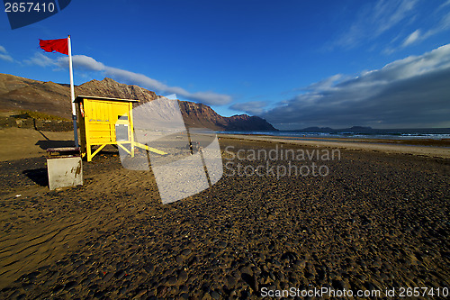 Image of lifeguard chair red flag in sp  rock stone sky cloud beach  