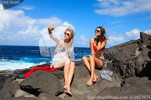 Image of two girls taking photo on the beach in summer holidays and vacat