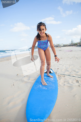 Image of Cute young girl standing on surfboard