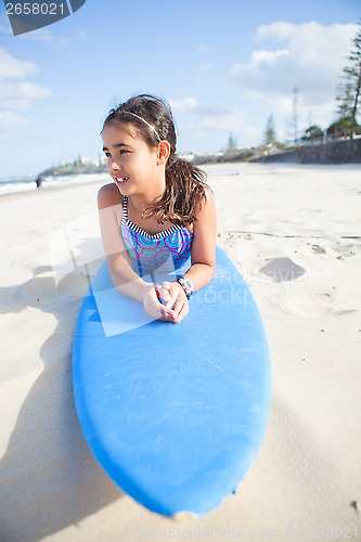 Image of Cute young girl lying on surfboard