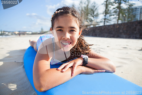 Image of Cute young girl lying on surfboard