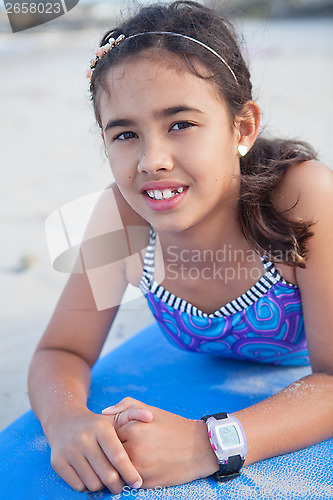 Image of Cute young girl lying on surfboard