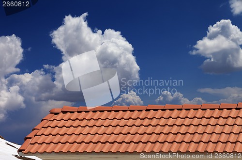 Image of Roof tiles, snowy slope and blue sky with clouds