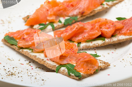 Image of Salted salmon on crispy bread with cheese and arugula