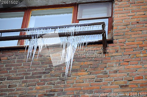 Image of Big icicles at a window, against a brick wall.