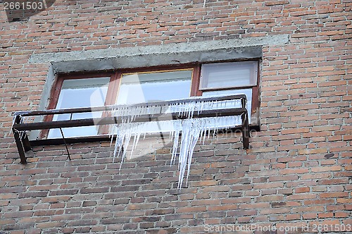 Image of Big icicles at a window, against a brick wall.