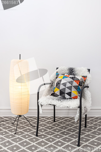 Image of Chair with bright cushion and elegant floor lamp
