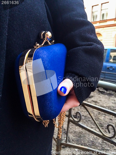 Image of Woman holding a blue handbag in her hand