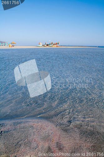 Image of Red sand clear seas and beach umbrellas